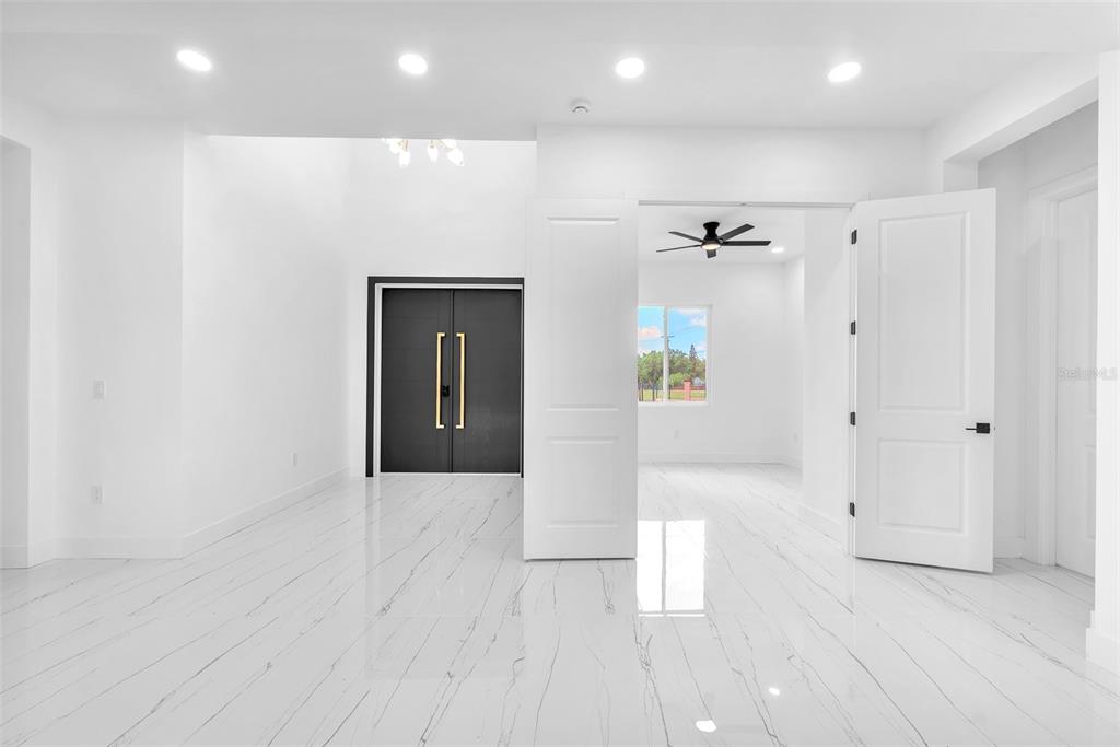 A bright room with white marble-look tile flooring, recessed lighting, and a dark double door — 11921 FORT KING HIGHWAY, THONOTOSASSA, FL