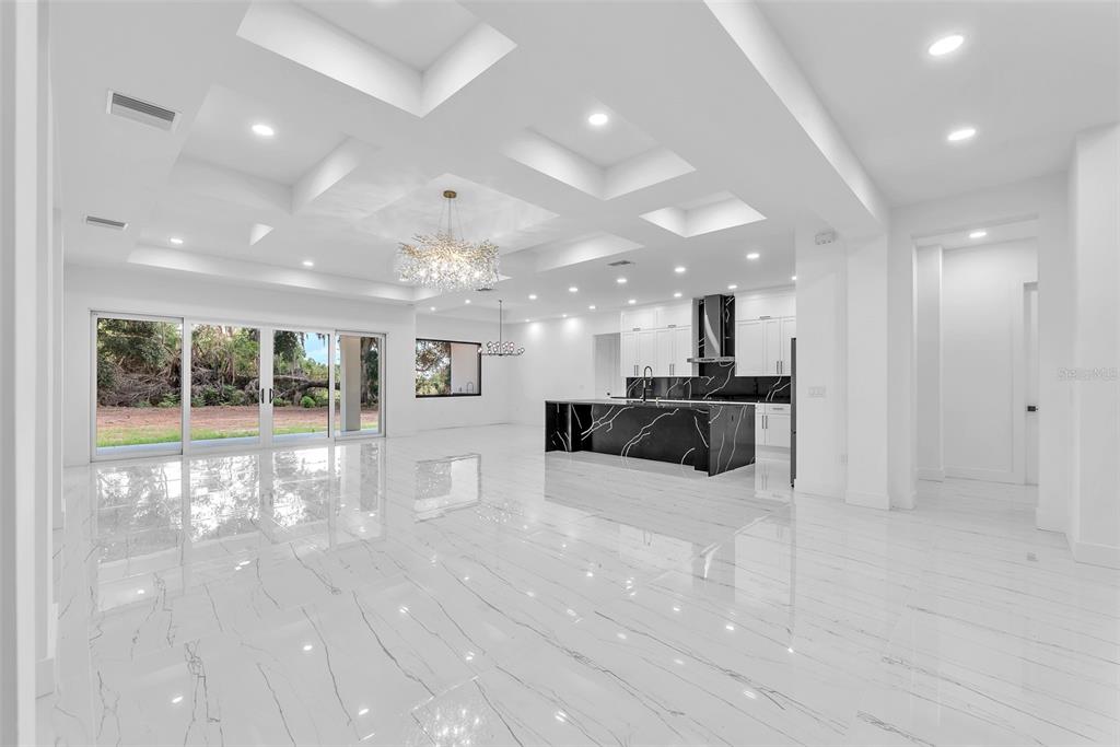 A bright, open-concept living area features white marble floors, a coffered ceiling, and a kitchen — 11921 FORT KING HIGHWAY, THONOTOSASSA, FL