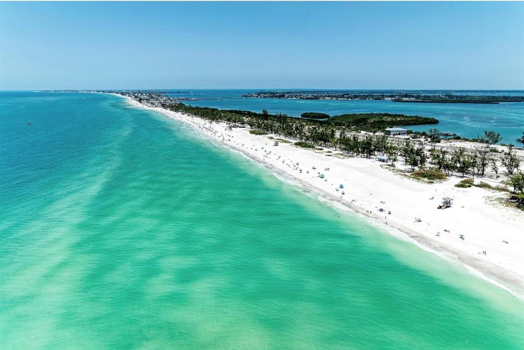 An aerial view of a long, sandy beach bordering turquoise water with trees and buildings — 580 LINLEY STREET, LONGBOAT KEY, FL