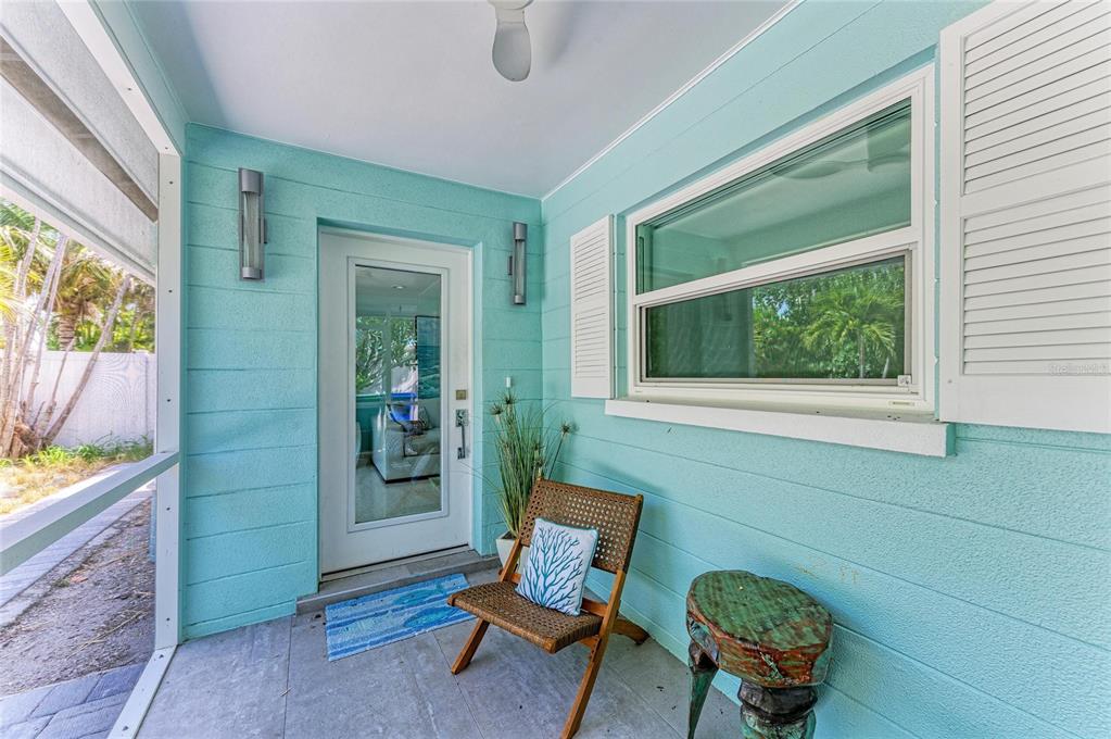 A covered porch with light blue horizontal siding, a glass door, and a wicker chair — 580 LINLEY STREET, LONGBOAT KEY, FL
