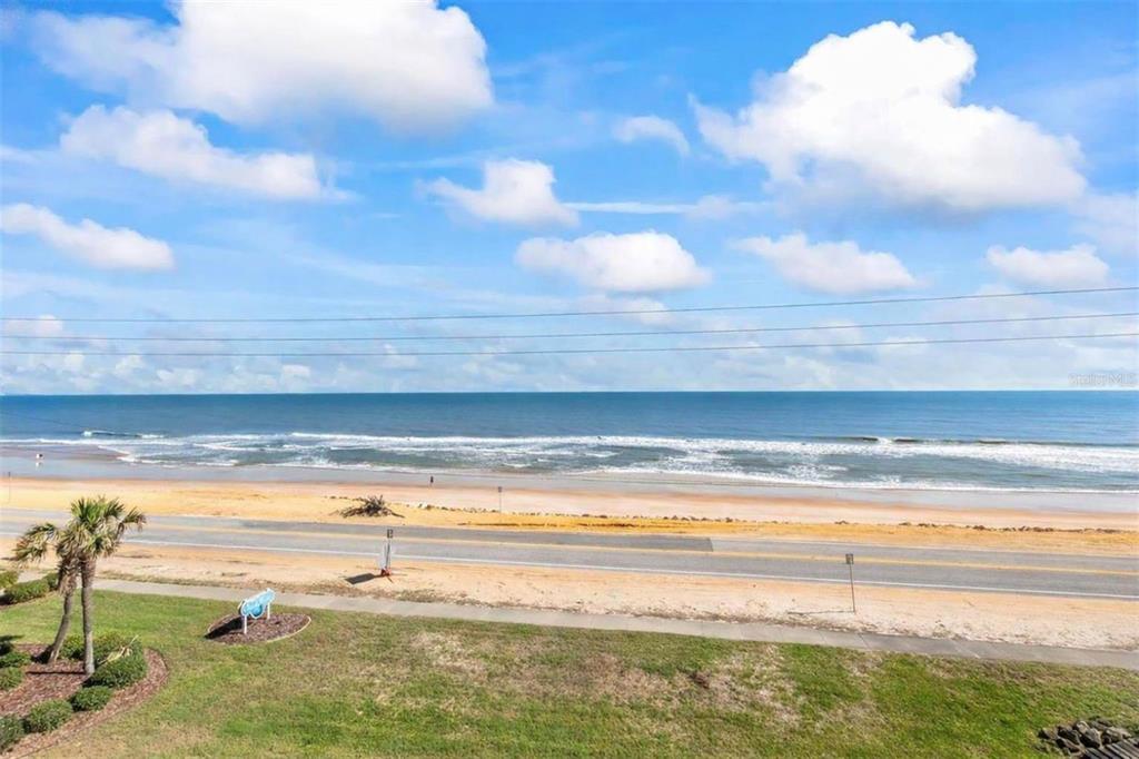 An elevated view of a sandy beach, ocean, and coastal road under a cloudy sky — 2700 OCEAN SHORE BOULEVARD UNIT 405, ORMOND BEACH, FL