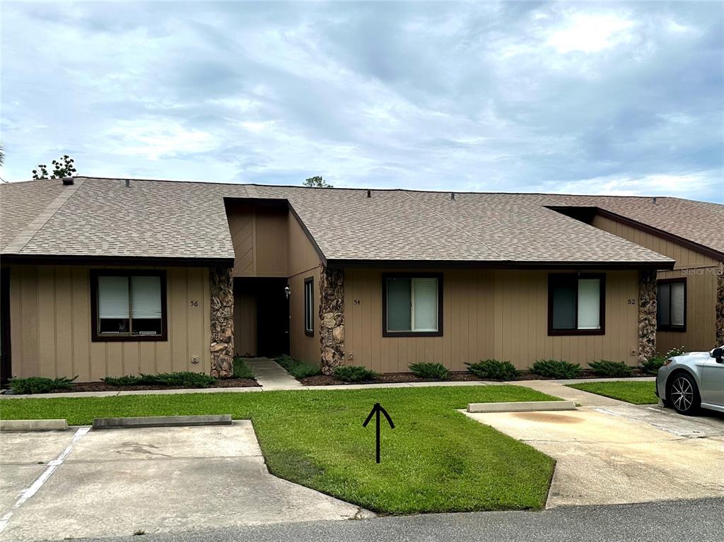 A single-story multi-unit residential building with brown siding, stone accents, and a shingled roof — 54 FOREST ROAD UNIT 54, FLAGLER BEACH, FL