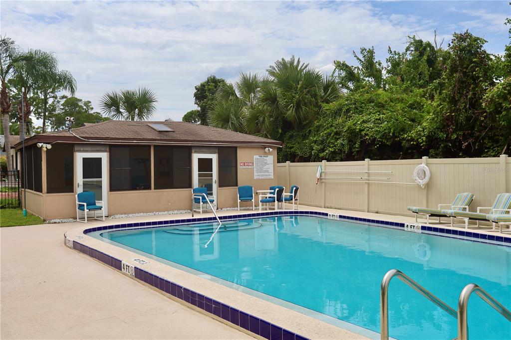 An outdoor swimming pool with a screened-in clubhouse and lounge chairs on a concrete deck — 54 FOREST ROAD UNIT 54, FLAGLER BEACH, FL