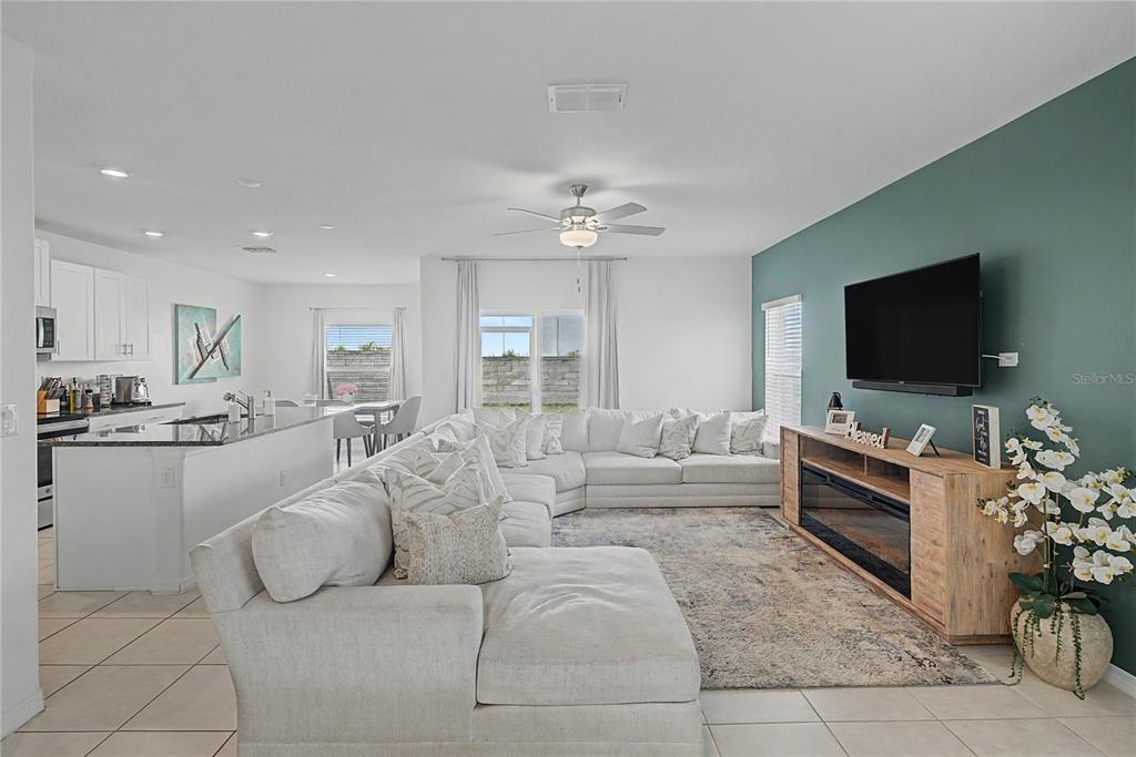 An open-concept living room features a large white sectional, a teal accent wall, and kitchen — 6357 BEVERLY HILLS DRIVE, ZEPHYRHILLS, FL