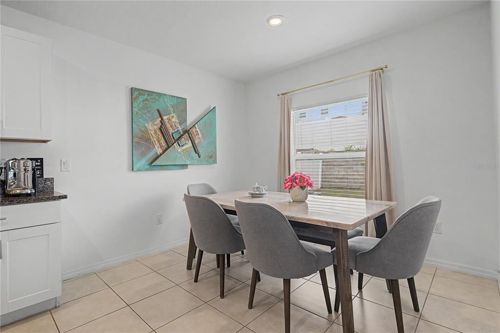 A dining area features a table with four gray chairs, tile flooring, and wall art — 6357 BEVERLY HILLS DRIVE, ZEPHYRHILLS, FL