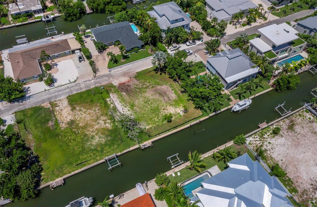 An aerial view of a vacant waterfront lot situated between two residential homes — 570 DE NARVAEZ DRIVE, LONGBOAT KEY, FL