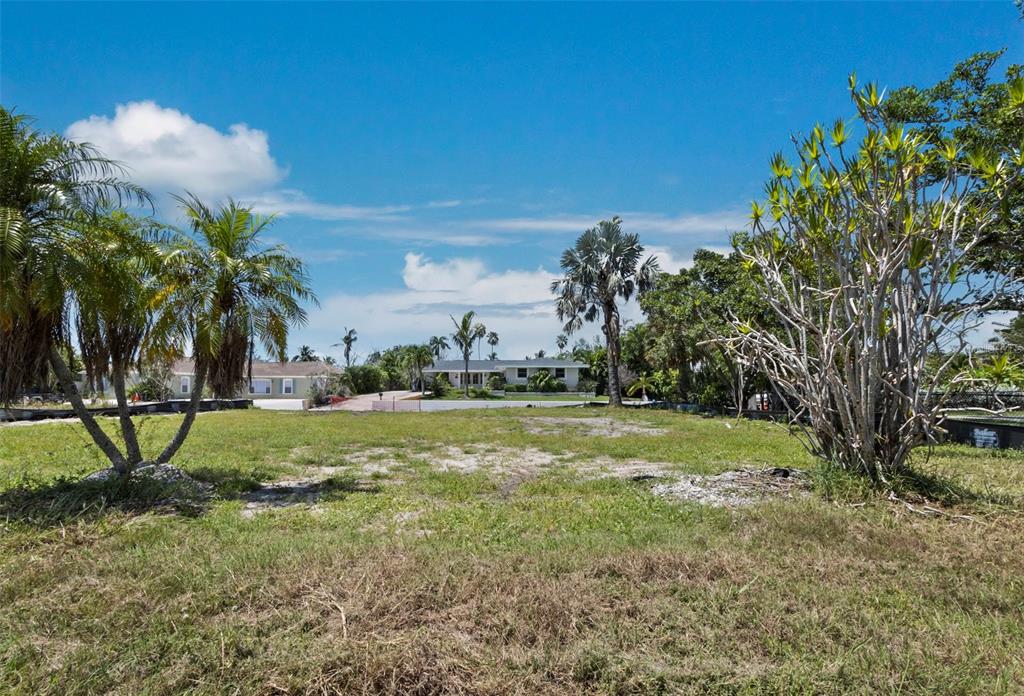 A grassy vacant lot with palm trees and a house in the background — 570 DE NARVAEZ DRIVE, LONGBOAT KEY, FL