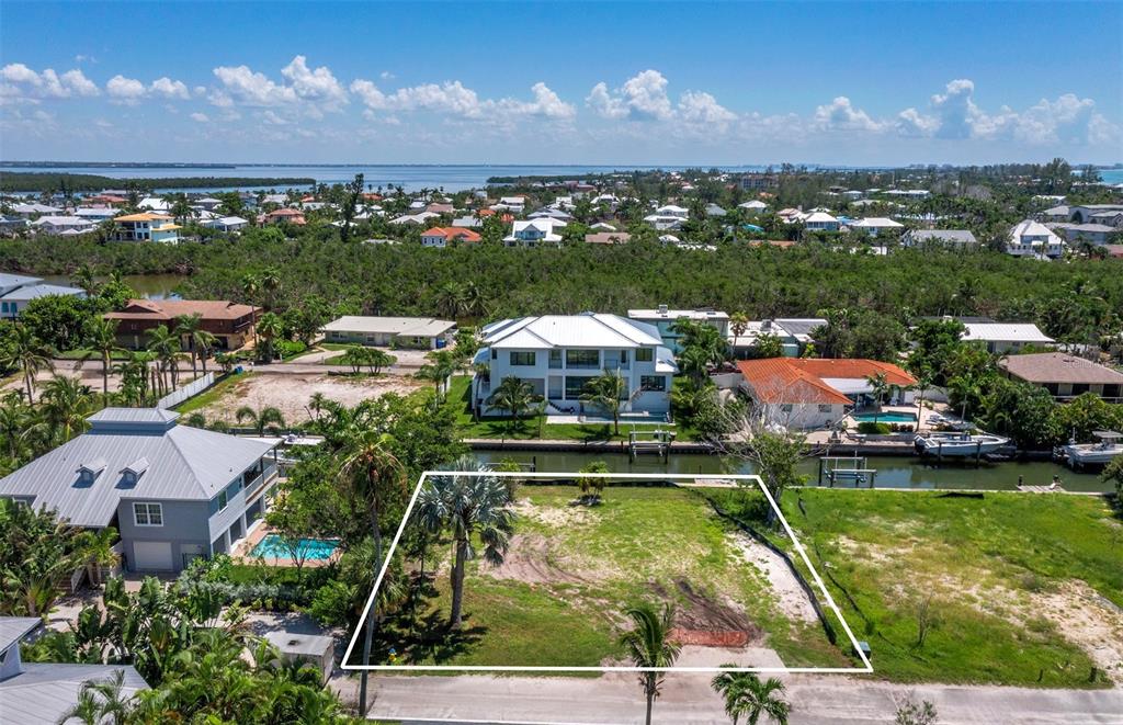 An aerial view shows a vacant waterfront lot outlined in white next to residential homes — 570 DE NARVAEZ DRIVE, LONGBOAT KEY, FL