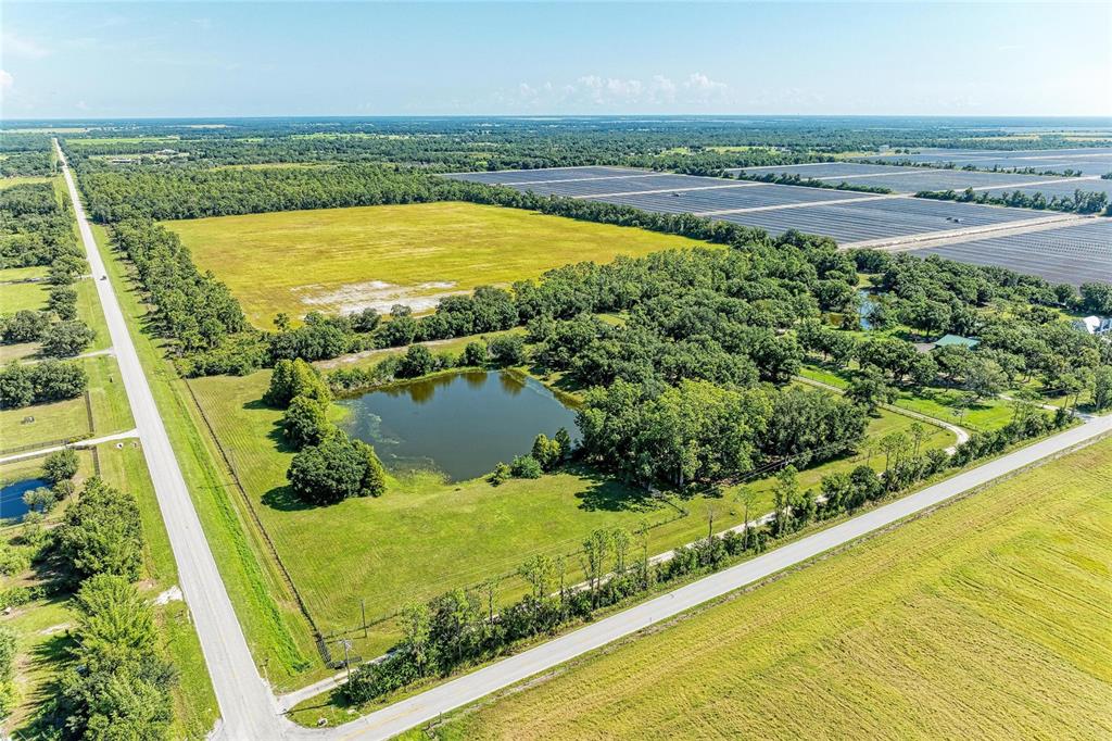 An aerial view shows a rural property with a pond, trees, and adjacent agricultural fields — 6055 COUNTY ROAD 675, MYAKKA CITY, FL