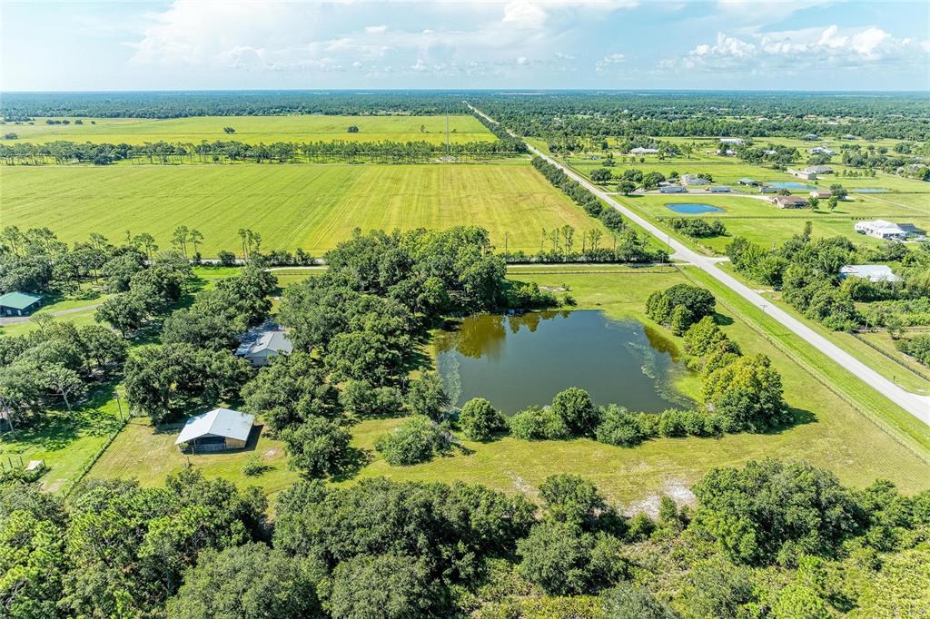 An aerial view shows a rural property with a pond, trees, and outbuildings near fields — 6055 COUNTY ROAD 675, MYAKKA CITY, FL