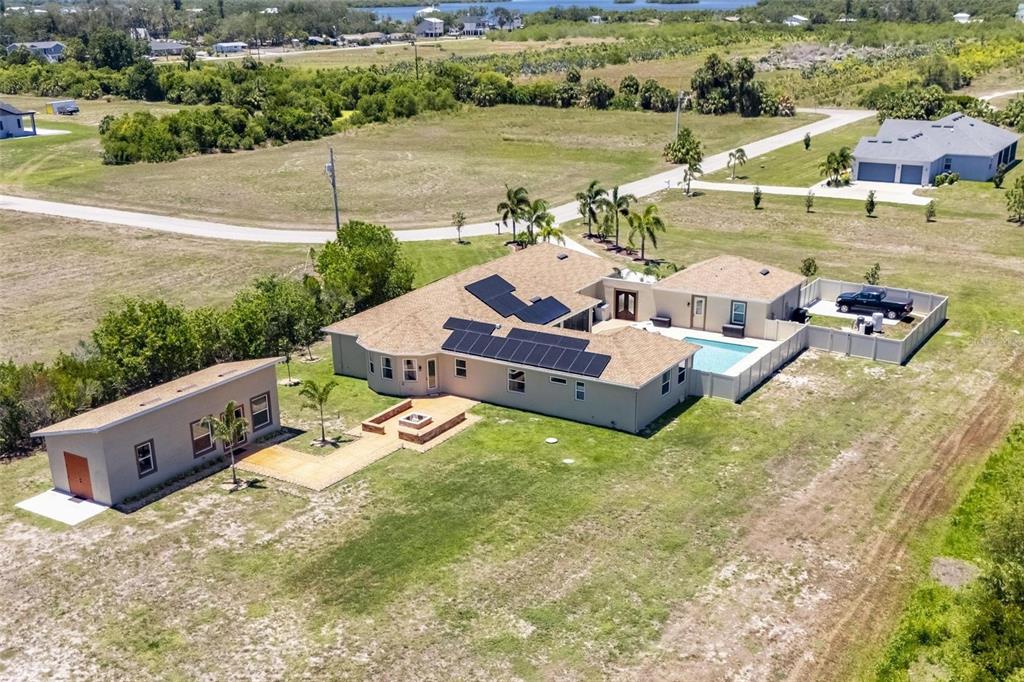 An aerial view shows a house with solar panels, a pool, and a detached garage — 3016 SMILODON TRAIL, RUSKIN, FL