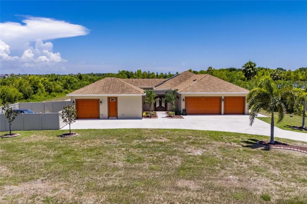 A single-story house with a three-car garage, tan stucco exterior, and a brown shingled roof — 3016 SMILODON TRAIL, RUSKIN, FL