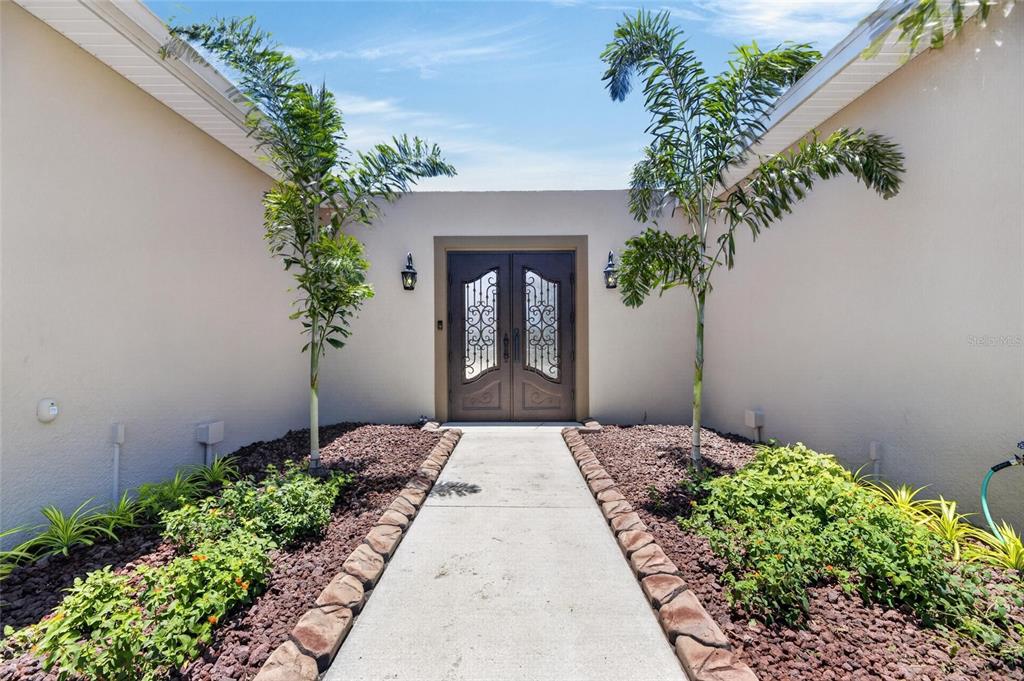 A concrete walkway leads to a double front door flanked by two palm trees — 3016 SMILODON TRAIL, RUSKIN, FL