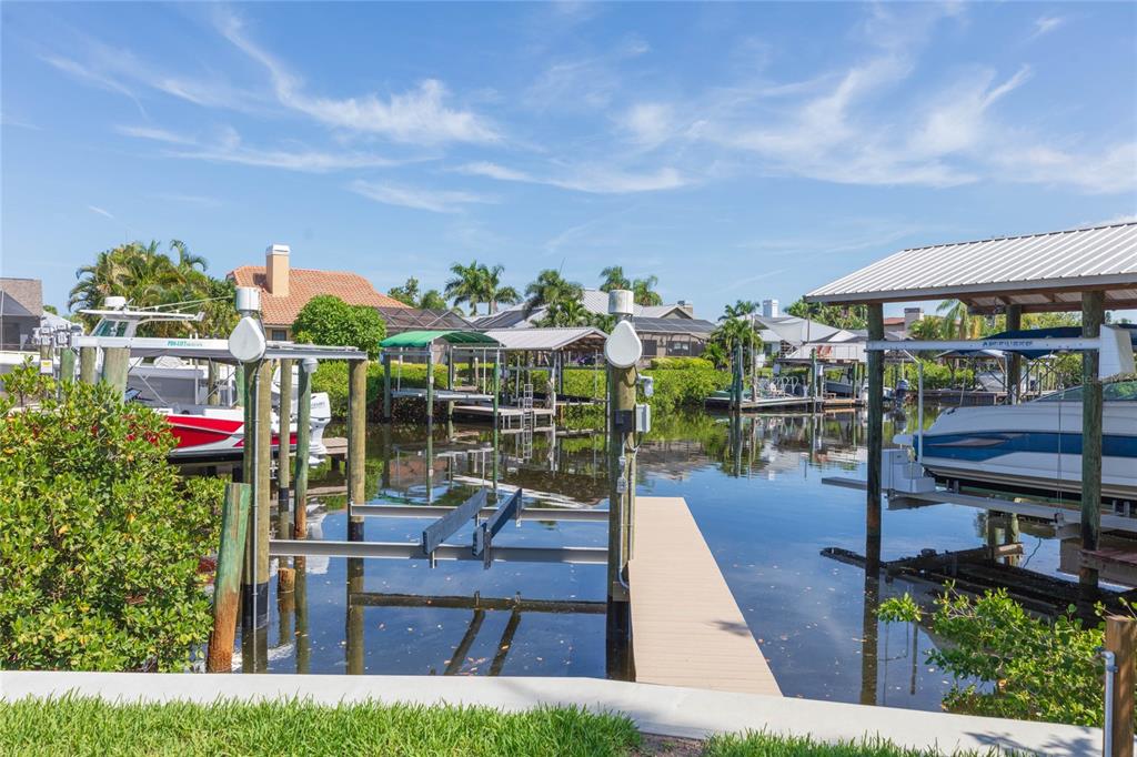 A boat dock with two covered slips sits on a canal behind a residential property — 6602 SEABIRD WAY, APOLLO BEACH, FL