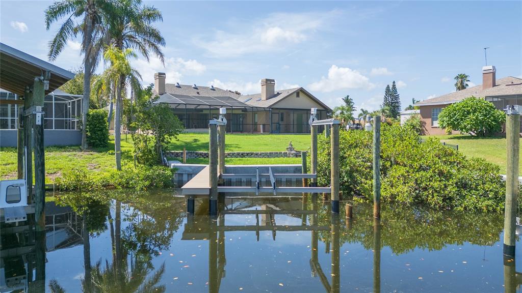 A view of a canal with a boat lift in front of a house with a lawn — 6602 SEABIRD WAY, APOLLO BEACH, FL