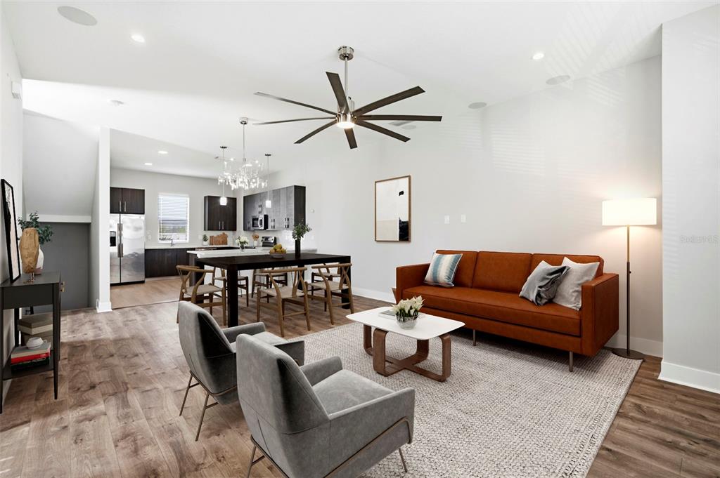 An open-concept living and dining area features wood-look flooring, a large ceiling fan, and furniture — 4810 W MCELROY AVENUE UNIT 7, TAMPA, FL