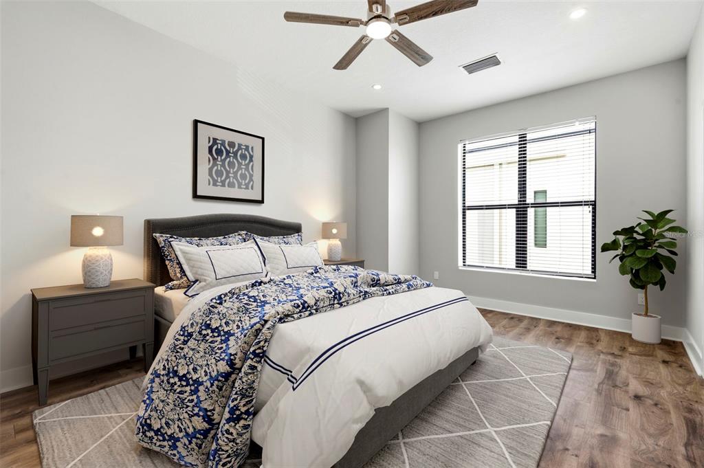 A bedroom features a bed with blue and white bedding, a ceiling fan, and wood flooring — 4810 W MCELROY AVENUE UNIT 7, TAMPA, FL