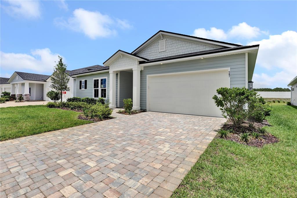 A light blue single-story house features a two-car garage and a paved stone driveway — 587 KNOTTED BIRCH AVENUE, ST AUGUSTINE, FL