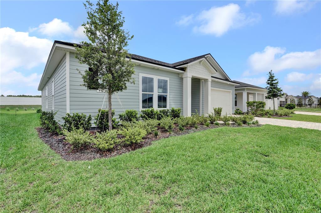 A light green, single-story house with a two-car garage and a landscaped front yard — 587 KNOTTED BIRCH AVENUE, ST AUGUSTINE, FL