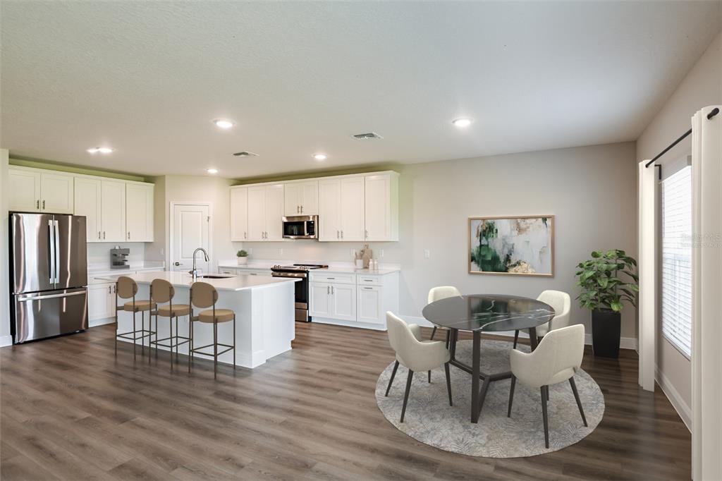 A kitchen and dining area with white cabinets, a central island, and wood-look flooring — 31717 BIENVILLE LANE, WESLEY CHAPEL, FL