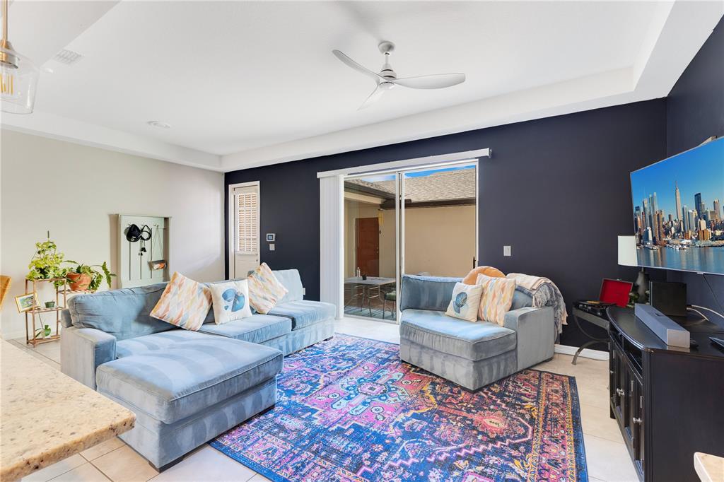 A living room features a blue sectional sofa, a colorful rug, and a sliding glass door — 5103 JONES ROAD, ST CLOUD, FL