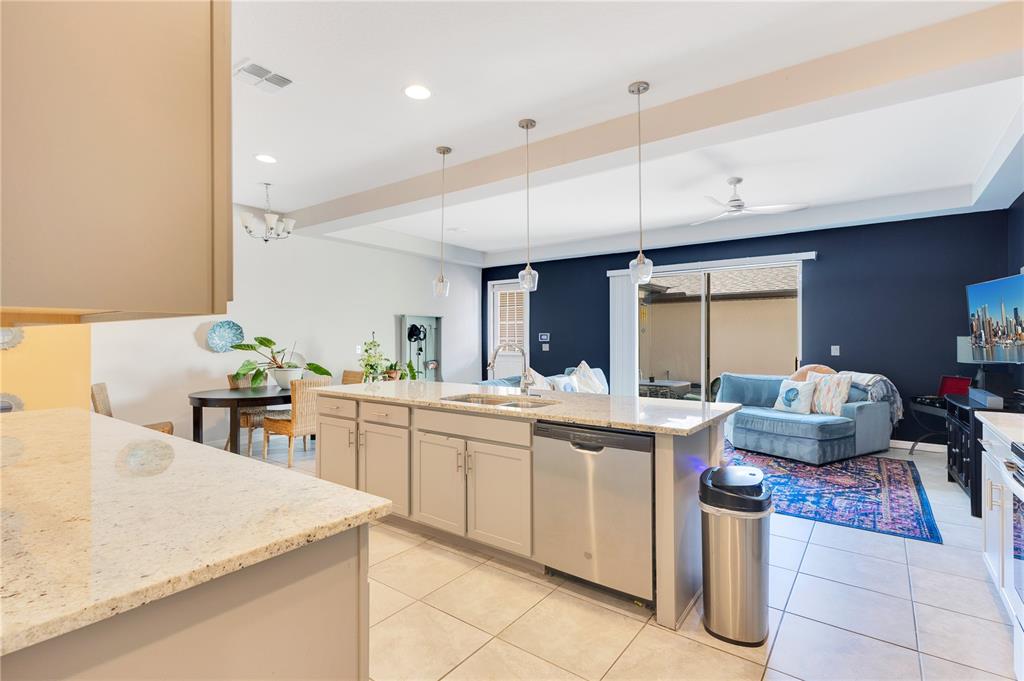 A kitchen with granite countertops and a central island overlooks an open-concept living area — 5103 JONES ROAD, ST CLOUD, FL