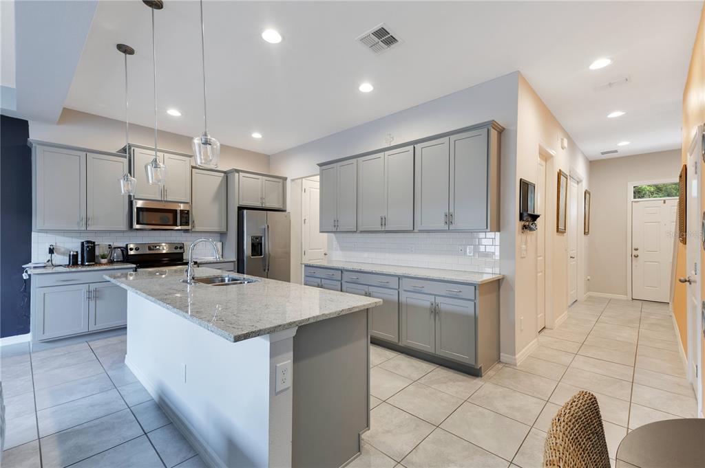A kitchen with gray cabinets, granite countertops, a central island, and light-colored tile flooring — 5103 JONES ROAD, ST CLOUD, FL