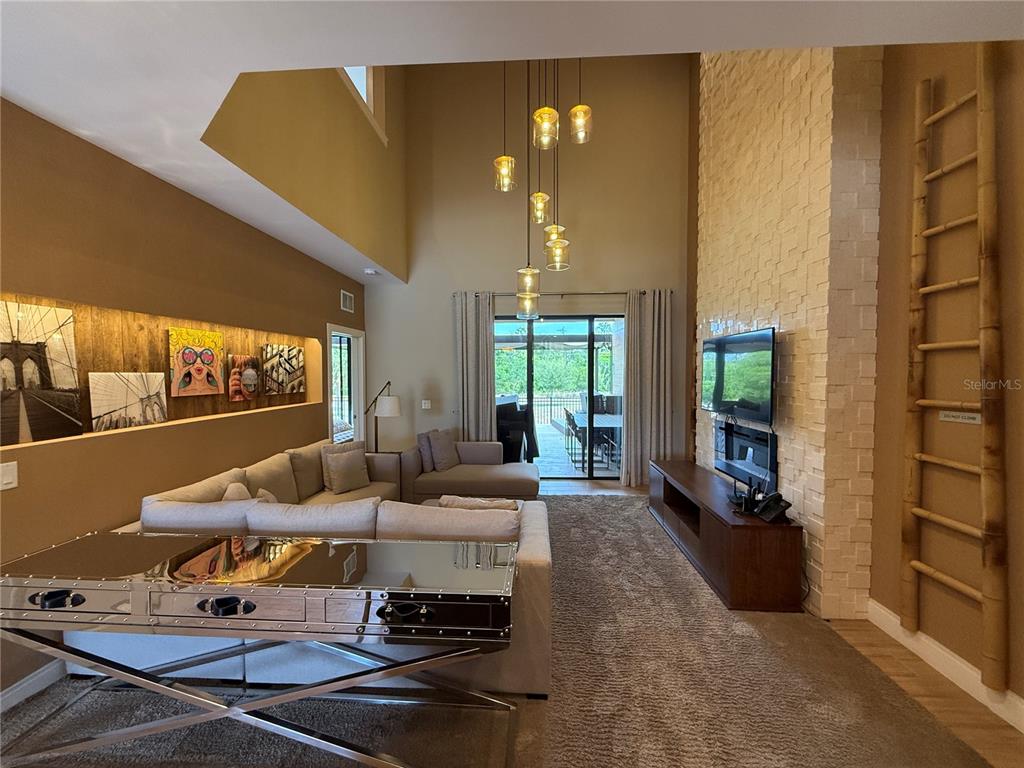 A living room features a stone fireplace, high ceilings with pendant lights, and a sectional sofa — 3065 ROCKEFELLER WAY, KISSIMMEE, FL