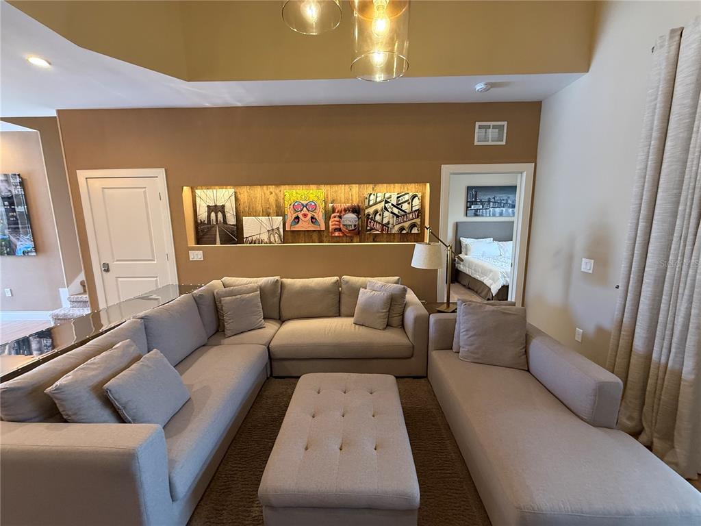 A living room features a large sectional sofa, a tufted ottoman, and a recessed wall display — 3065 ROCKEFELLER WAY, KISSIMMEE, FL