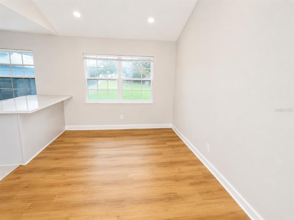 An empty dining area features light wood-look flooring, white walls, and a window — 118 2ND STREET NW, RUSKIN, FL