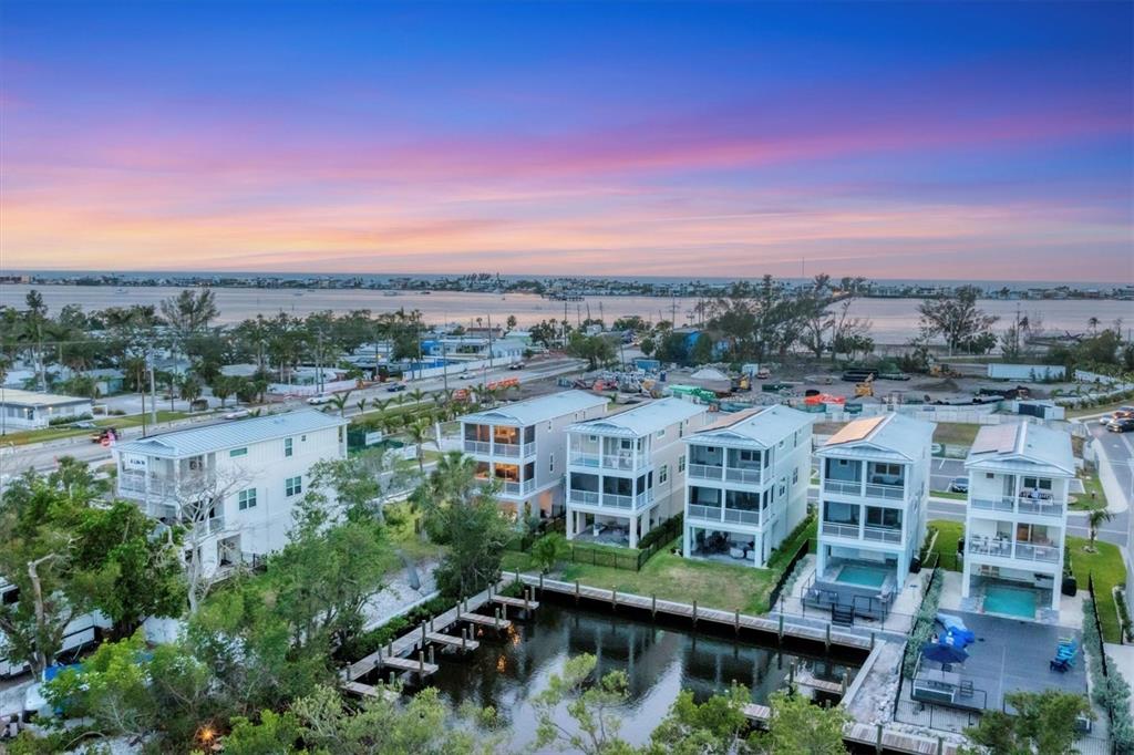 An aerial view shows several modern white houses with balconies situated along a small canal — 4357 MARINA VIEW WAY, CORTEZ, FL