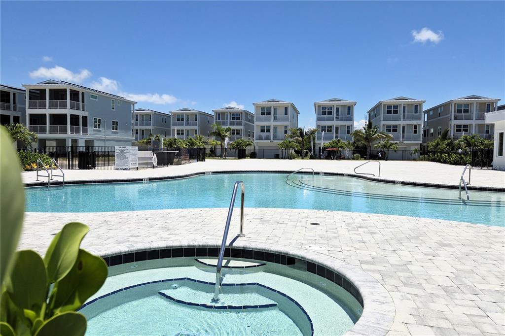 A swimming pool and hot tub are situated in front of several multi-story residential buildings — 4357 MARINA VIEW WAY, CORTEZ, FL