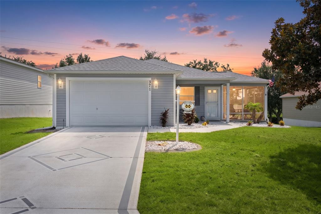 A single-story house with gray siding, a white garage door, and a screened-in front porch — 371 ARBELLA LOOP, THE VILLAGES, FL