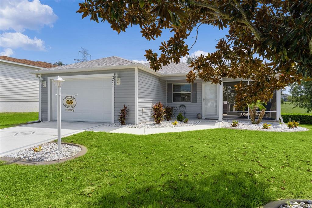 A single-story house with gray siding, a garage, and a screened-in front porch — 371 ARBELLA LOOP, THE VILLAGES, FL