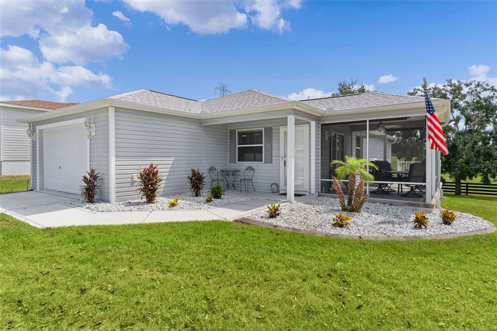 A single-story house with light gray siding, a garage, and a screened-in front porch — 371 ARBELLA LOOP, THE VILLAGES, FL