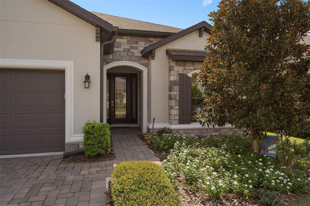 The exterior of a house features a stone facade, a paved walkway, and a front door — 1197 ESPERANZA RIDGE ROAD, CLERMONT, FL