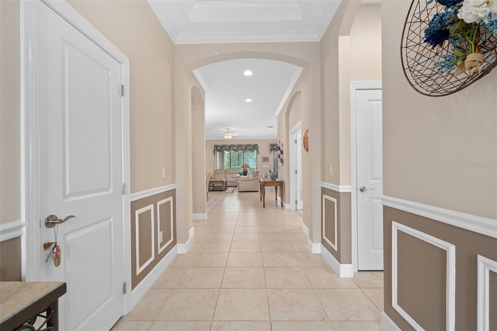 A tiled hallway leads from the entryway toward a living room with arched architectural details — 1197 ESPERANZA RIDGE ROAD, CLERMONT, FL
