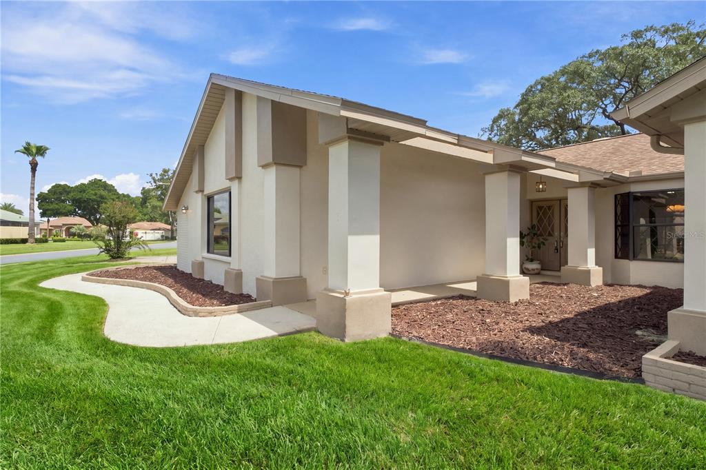 A view of a house exterior featuring a covered entryway with columns and mulch beds — 9429 COBBLER COURT, WEEKI WACHEE, FL