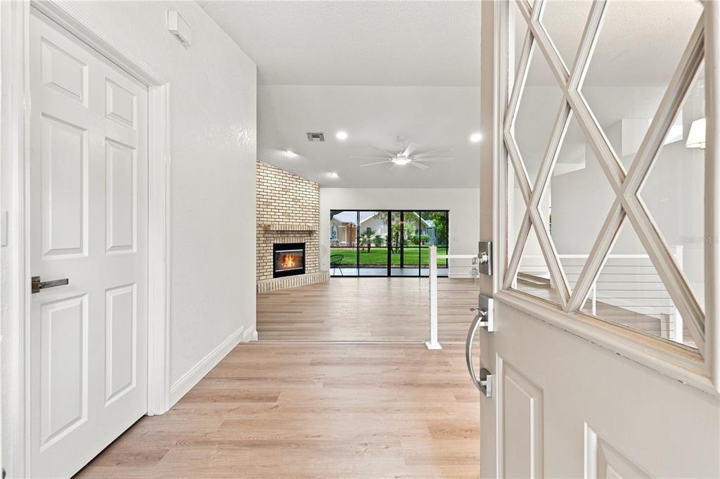 An entryway opens into a living room featuring light wood flooring and a brick fireplace — 9429 COBBLER COURT, WEEKI WACHEE, FL