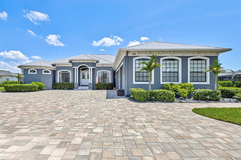 A gray single-story house with a metal roof and a large paver driveway — 1911 148TH COURT E, BRADENTON, FL