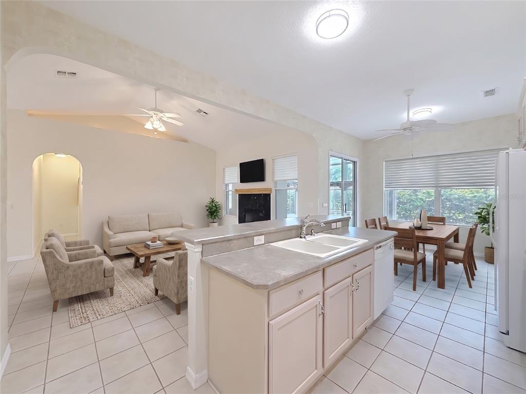 A kitchen with light cabinets and a double sink overlooks an open-concept living and dining area — 11932 SE 179TH STREET, SUMMERFIELD, FL