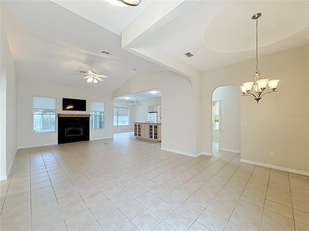 An open-concept living and dining area features tile flooring, a fireplace, and vaulted ceilings — 11932 SE 179TH STREET, SUMMERFIELD, FL