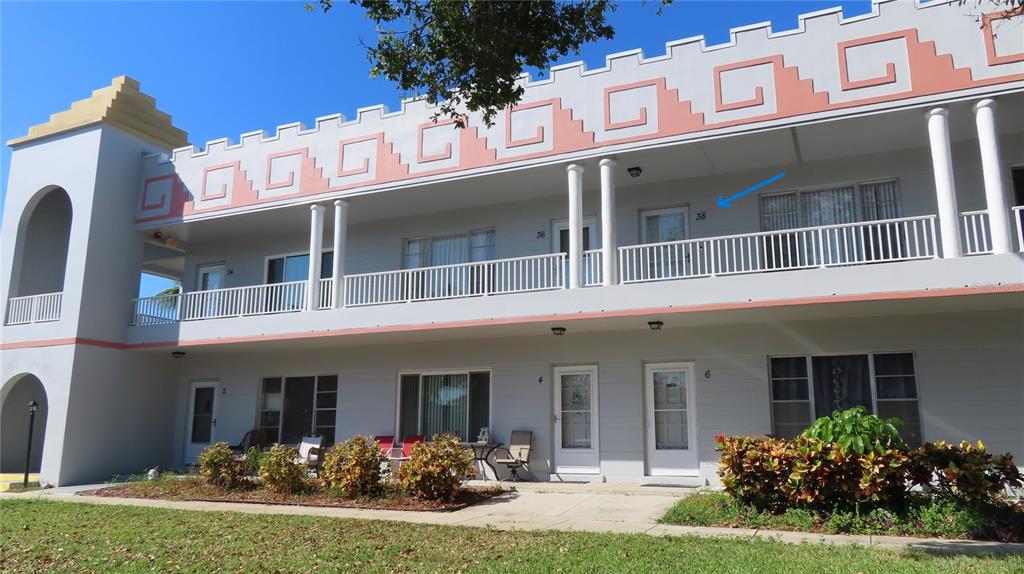 A two-story apartment building with a decorative pink parapet and a blue arrow pointing upward — 2100 WORLD PARKWAY BOULEVARD UNIT 38, CLEARWATER, FL