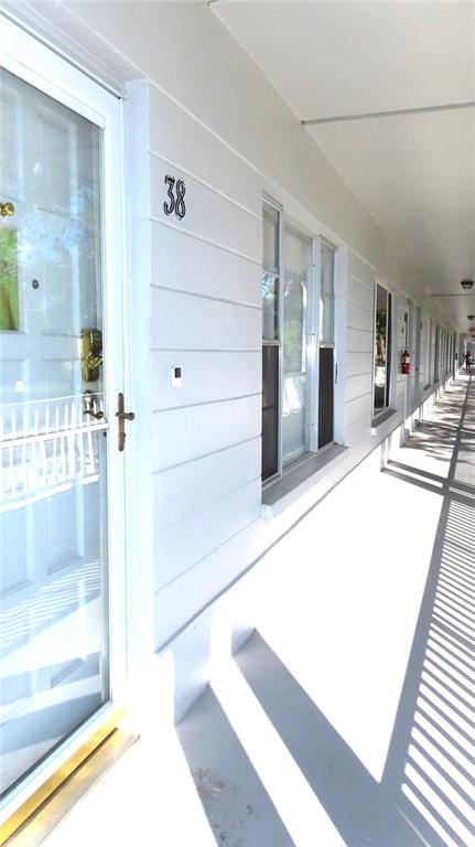 A view of an exterior apartment walkway with a white door labeled 38 — 2100 WORLD PARKWAY BOULEVARD UNIT 38, CLEARWATER, FL