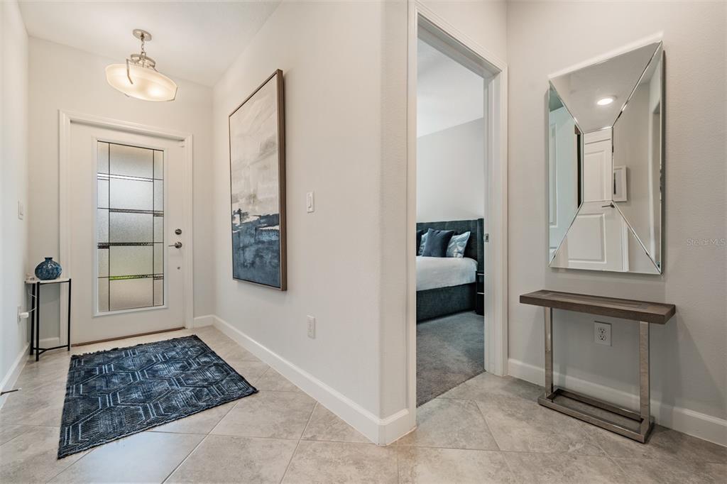 A bright entryway features tile flooring, a front door with glass panels, and a console table — 10191 ECHO DOCK LOOP, SAN ANTONIO, FL