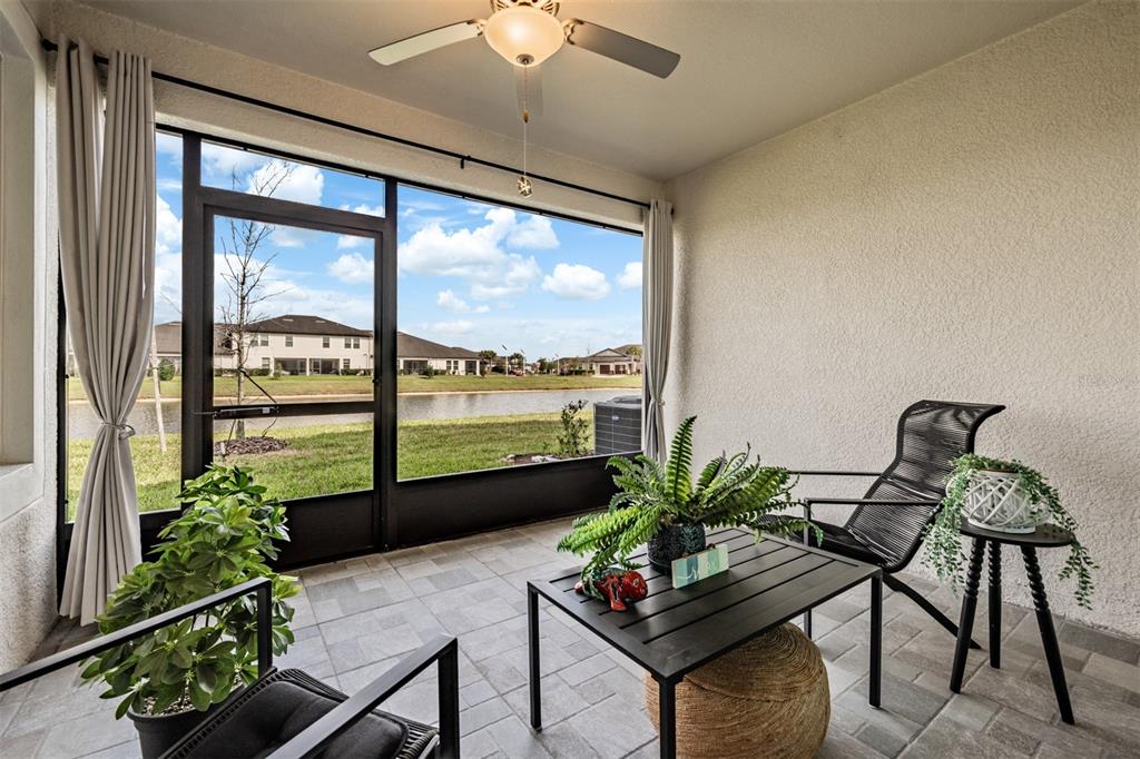 A screened-in patio features tiled flooring, a ceiling fan, and a view of a pond — 10191 ECHO DOCK LOOP, SAN ANTONIO, FL