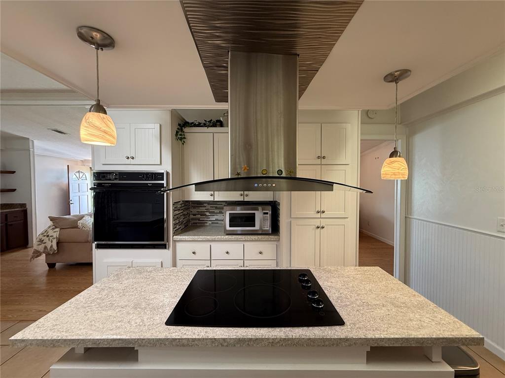 A kitchen island with a black cooktop sits beneath a stainless steel range hood — 12501 ULMERTON ROAD UNIT 181, LARGO, FL