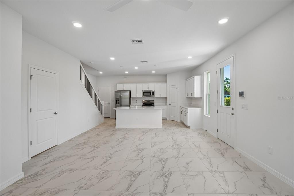 A bright, open-concept kitchen features white cabinetry, a central island, and light marble-patterned tile flooring — 616 SILVER STREAM COURT, BRANDON, FL
