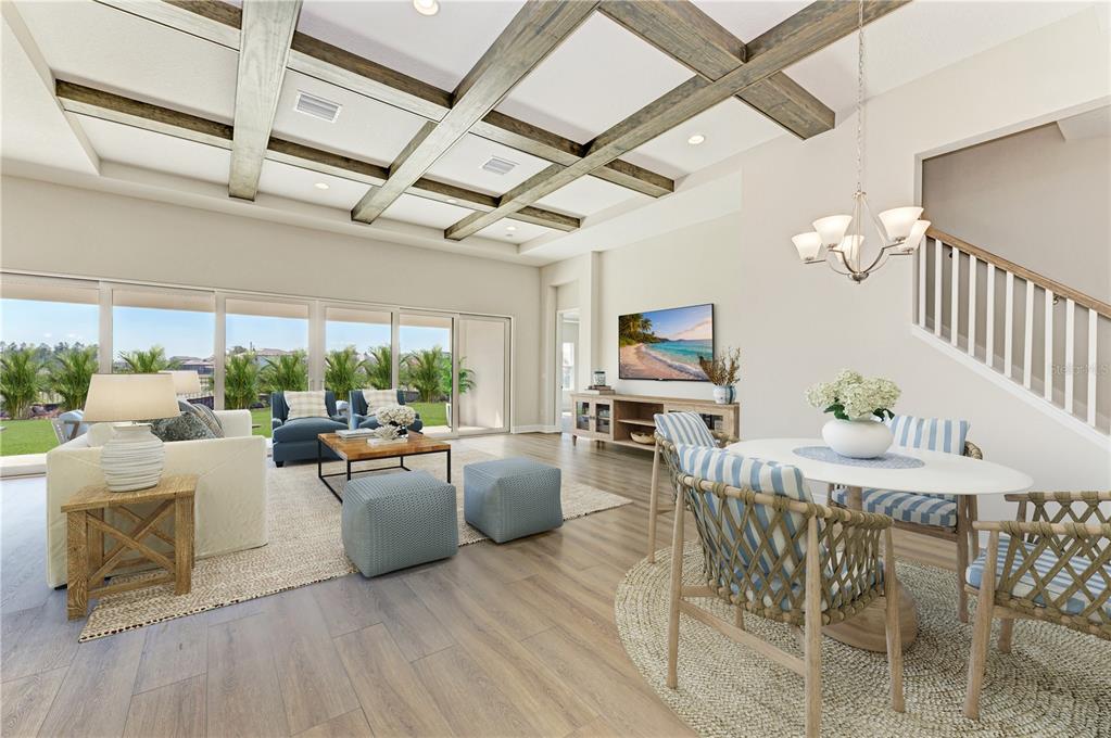 An open-concept living and dining area features wood-beam ceilings, light flooring, and large sliding doors — 35576 BIG HAWK DRIVE, ZEPHYRHILLS, FL