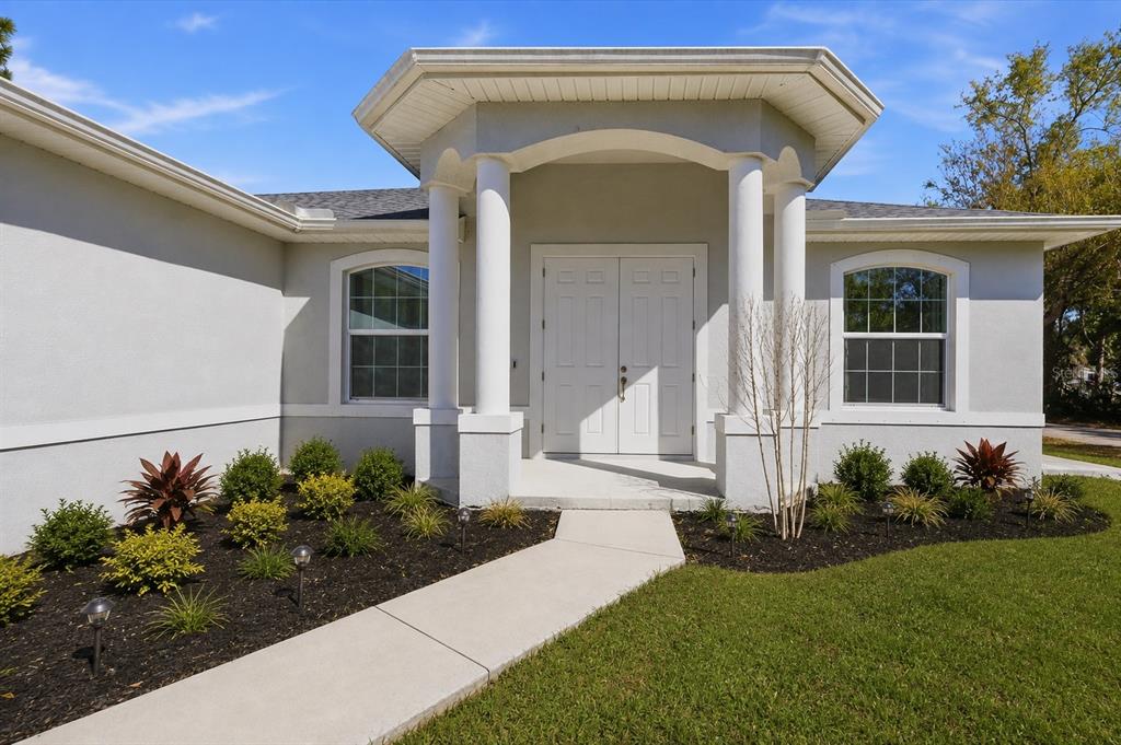 A light-colored house exterior features a covered entryway with two white columns and double doors — 3498 DUNKIRK STREET, PORT CHARLOTTE, FL